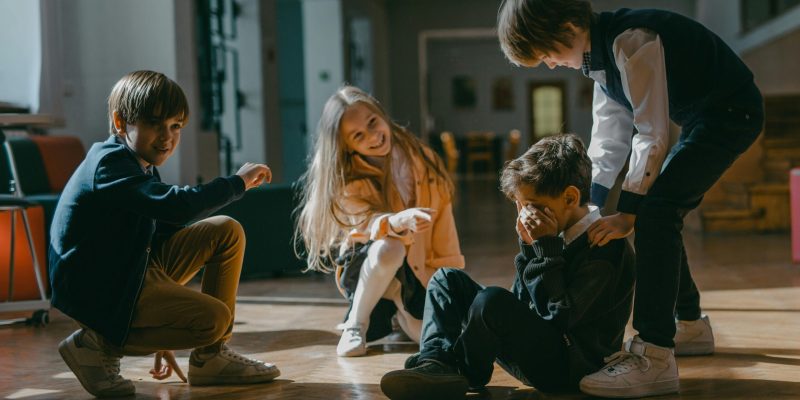 Four kids engaged in a playful or bullying encounter inside a school.