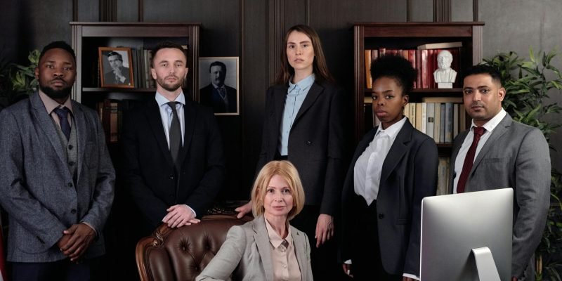 Diverse group of professionals in corporate attire posing confidently in an office environment.